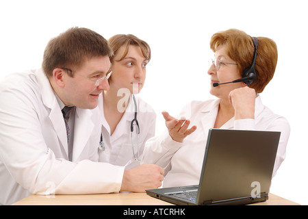 Zwei junge Praktikanten medizinisches Problem mit Senior Beratung Arzt tragen Kopfhörer sitzen hinter Schreibtisch mit Laptop in weiß Stockfoto