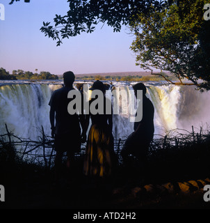 Rückansicht von drei Personen in der Silhouette, die auf der Suche an den Victoria Fällen in Matabeleland Provinz Simbabwe Afrika Stockfoto