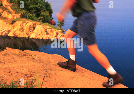 Nahaufnahme von einem Wanderer Beine zu Fuß auf einem Felsvorsprung mit einem See unten Stockfoto