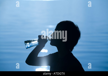 Silhouette der jungen Frau trinkt Stockfoto