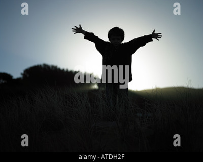 Junge mit Armen, breiten Junge stand auf Bergrücken mit Licht von hinten mit Armen, breiten und Fingern heraus gestreckt Stockfoto