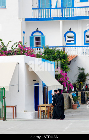 Zwei griechische orthodoxe Priester gehen vor dem Hotel Calypso, Lipsi, Dodekanes, Griechenland Stockfoto