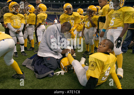 Ein Spieler erhält seinen Knöchel mit Klebeband vor einem jungen Fußballspiel in Detroit s Police Athletic League gelb Stockfoto