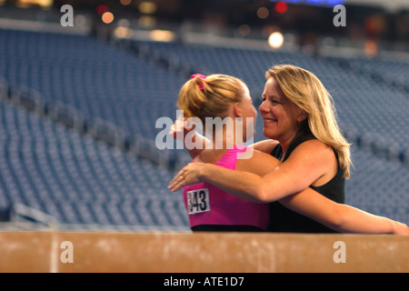 Ein Coach schmiegt sich ein Teilnehmer in der Gymnastik-Wettbewerb während der AAU Junior Olympics in Detroit Stockfoto