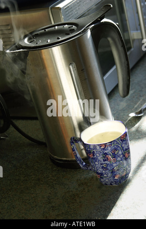 Abgekochtes Wasser im Cup mit Edelstahl Wasserkocher Dampf steigt von beiden Stockfoto