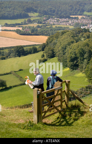 EIN PAAR WANDERER ÜBERPRÜFEN IHRE ORDNANCE SURVEY MAP UND NEHMEN IN EINER ANSICHT VON GLOUCESTERSHIRE UK AUS ULEY BEGRABEN DOWNHAM HILL UND D Stockfoto