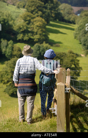 EIN PAAR WANDERER NEHMEN IN EINER ANSICHT VON GLOUCESTERSHIRE UK AUS ULEY BEGRABEN ZU DOWNHAM HILL BEKANNTEN LOKAL ALS POCKEN HILL WEGEN ONC Stockfoto