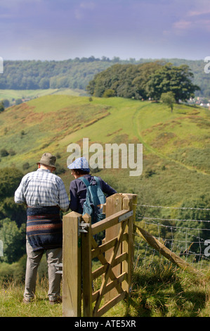 EIN PAAR WANDERER NEHMEN IN EINER ANSICHT VON GLOUCESTERSHIRE UK AUS ULEY BEGRABEN ZU DOWNHAM HILL BEKANNTEN LOKAL ALS POCKEN HILL WEGEN ONC Stockfoto