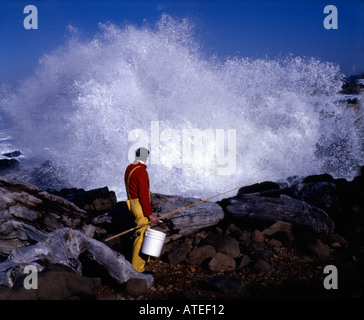 Vermessung der felsigen Küste, wo er plant, seine Linie in den tosenden Ozean Fall, Surf-Fischer Stockfoto