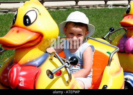 Kleiner Junge in Ente Fahrt, junge sitzen im Zug auf Spielplatz Stockfoto