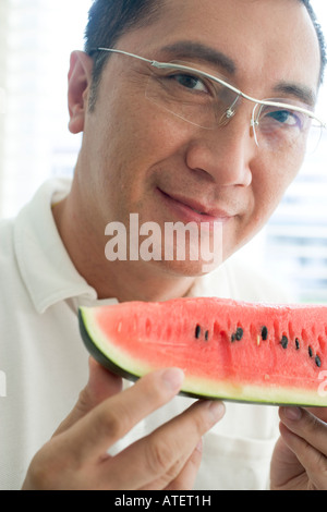 Porträt von einem reifen Mann hält ein Stück Wassermelone Stockfoto