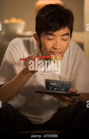 Junger Mann essen Nudeln. Stockfoto