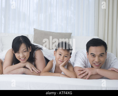 Porträt von Eltern mit ihrem Sohn und Tochter auf dem Bett lächelnden liegend Stockfoto