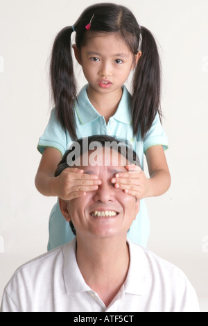 Porträt eines Mädchens, das ihr Großvater Augen bedecken Stockfoto
