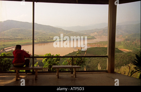 Mann sitzen Bank Rand Tal Uhr Blick beobachten herrliche atemberaubende Wasserlauf Mekong River Huay Xai Laos Südostasien Stockfoto