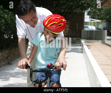 Reifer Mann lehrt seine Enkelin, wie Fahrrad fahren Stockfoto