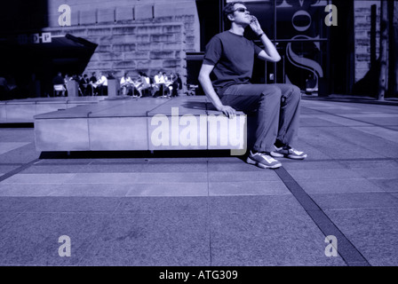 Mann mit Handy auf der Straße sitzen Stockfoto