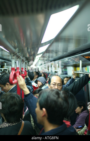 Alle Passagiere, die auf der Suche beschäftigt und müde Hüten ihr eigenes Geschäft in Hong Kong MTR Zug voller Stockfoto
