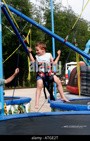 Junge auf Bungee-Bounce schwingt am Sicherheitsgurt und Seile Stockfoto