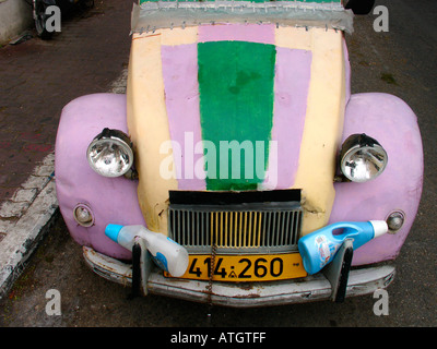 Vorderansicht des alten Citroën 2CV mit mehrfarbigem Farbschema und zwei Kunststoffwaschmittelflaschen am vorderen Stoßfänger. Stockfoto