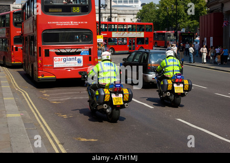 Polizei-Motorradfahrer in Warteschlange des Verkehrs hinter London Busse Stockfoto