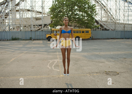 Junge Frau springt in Aufregung während auf einem leeren Parkplatz hinter die Cyclone-Achterbahn in Coney Island, Brooklyn Stockfoto