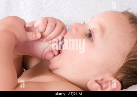 6 Monate altes Baby er Zehen in Mund Stockfoto