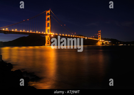 Golden Gate Bridge von Fort Point-Aussichtspunkt gesehen leuchtet in der Nacht mit Sternspuren am Himmel dahinter Stockfoto
