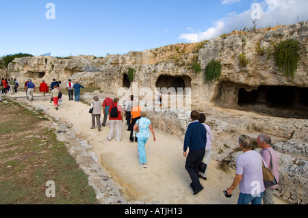 Touristen zu Fuß die Straße des byzantinischen Felsen gehauene Gräber entlang des oberen Randes der antiken griechischen Theatrein Syrakus, Sizilien, Italien Stockfoto