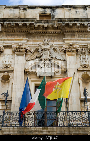 Detail der Fassade eines städtischen Gebäudes an der Piazza del Duomo in Syrakus auf Sizilien; die Flagge von Sizilien ist auf der rechten Seite Stockfoto