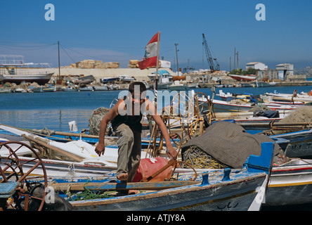 Junge hocken und sich über Fischerboote in der Küstenstadt Saida, Libanon Stockfoto