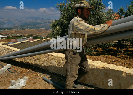 Ein männlicher Arbeitnehmer tragen ein Bündel von Rohren in Beirut Libanon Stockfoto