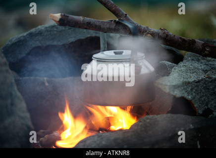 Sonnenuntergang und einem Wasserkocher am knisternden Flammen eines Lagerfeuers Zeit für eine Tasse Tee Stockfoto