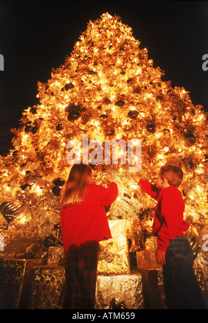 Jungen und Mädchen unter verziert hell riesigen Weihnachtsbaum Stockfoto