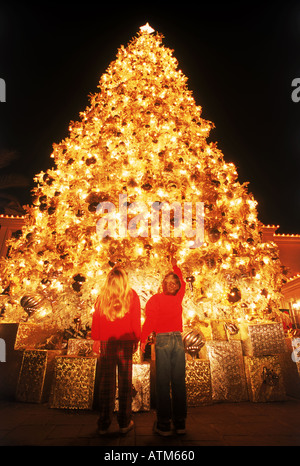 Jungen und Mädchen unter verziert hell riesigen Weihnachtsbaum Stockfoto