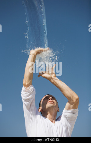 Mann immer mit Wasser vor einem blauen Himmel spritzte Stockfoto