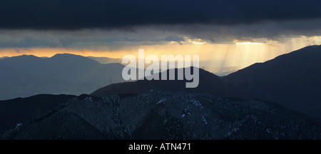 Panorama-Bild der erstaunliche Sonnenlicht Strahlen fallen durch schwere schwarze Gewitterwolken über dem Kongo-Bergkette in Osaka Japan Stockfoto