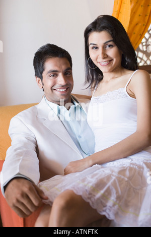 Junge Frau sitzt auf dem Schoß eines jungen Mannes Stockfoto
