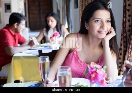 Junge Frau sitzt in einem Restaurant mit einer Mitte erwachsenes paar etwas zu Essen im Hintergrund Stockfoto