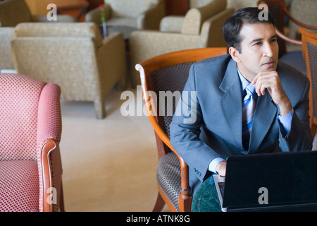 Geschäftsmann, sitzen vor einem Laptop mit der Hand am Kinn Stockfoto