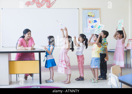 Lehrer, die Überprüfung von Zeichnungen von Schülern in einer Klasse Stockfoto