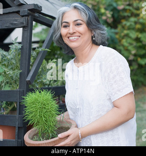 Nahaufnahme einer reifen Frau mit einer Topfpflanze Stockfoto