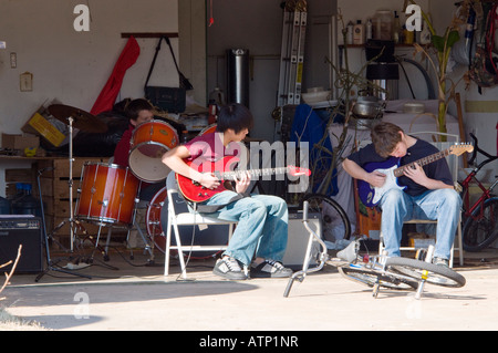 Drei Jungs im Teenageralter, die eine Garagenband gebildet haben üben Sie Musik in einer Garage in Oklahoma City, Oklahoma, USA. Stockfoto