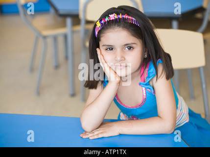Porträt eines Mädchens mit der Hand am Kinn in einem Klassenzimmer zu sitzen Stockfoto