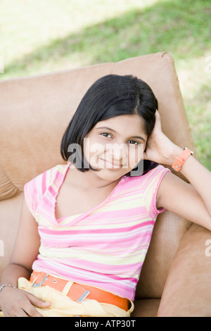 Porträt eines Mädchens in einem Sessel sitzend und lächelnd Stockfoto