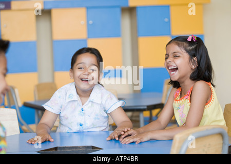 Zwei Schulmädchen mit ein Schuljunge Lachen in einem Klassenzimmer Stockfoto