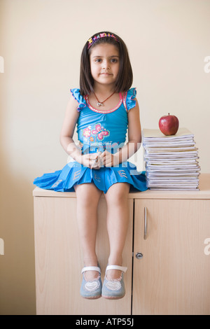 Porträt eines Mädchens sitzen in der Nähe von einem Stapel Bücher auf einem Schrank Stockfoto