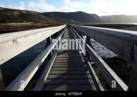 hölzerne Fußgängerbrücke über den Fluss in Richtung Hügel in Glen Muick in der Nähe von Ballater, Aberdeenshire, Schottland, UK Stockfoto