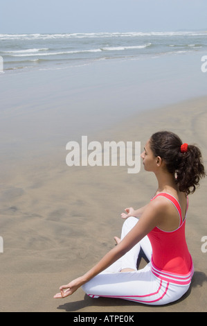 Seitenansicht einer jungen Frau, meditieren am Strand Stockfoto