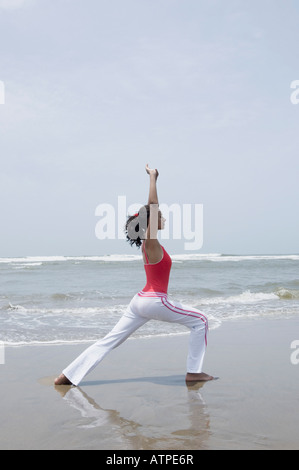 Seitenansicht einer jungen Frau praktizieren Yoga am Strand Stockfoto